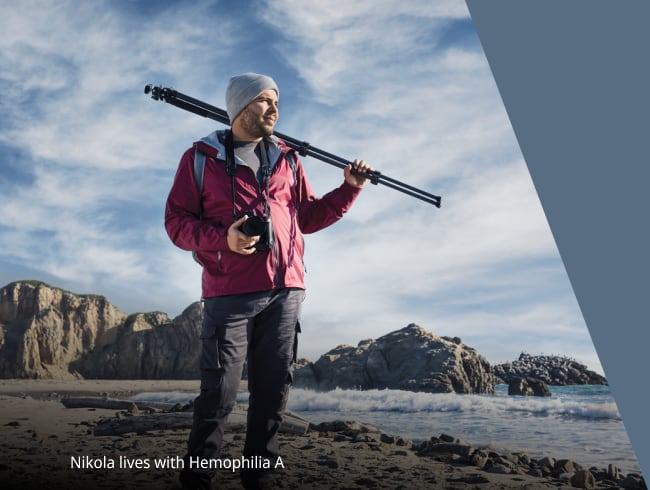 person standing on a beach, holding camera equipment and looking into the distance