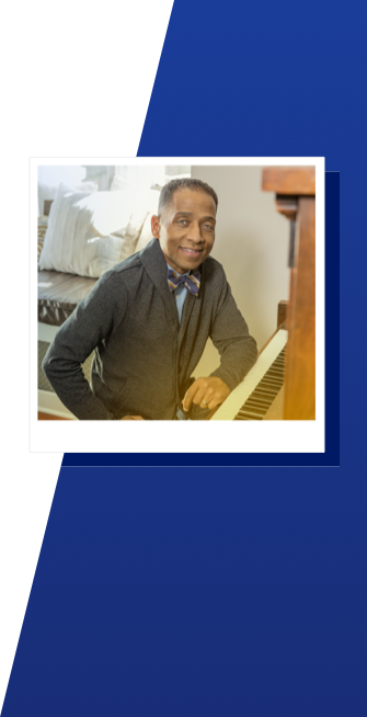 A man named Timothy sits at the piano and smiles.